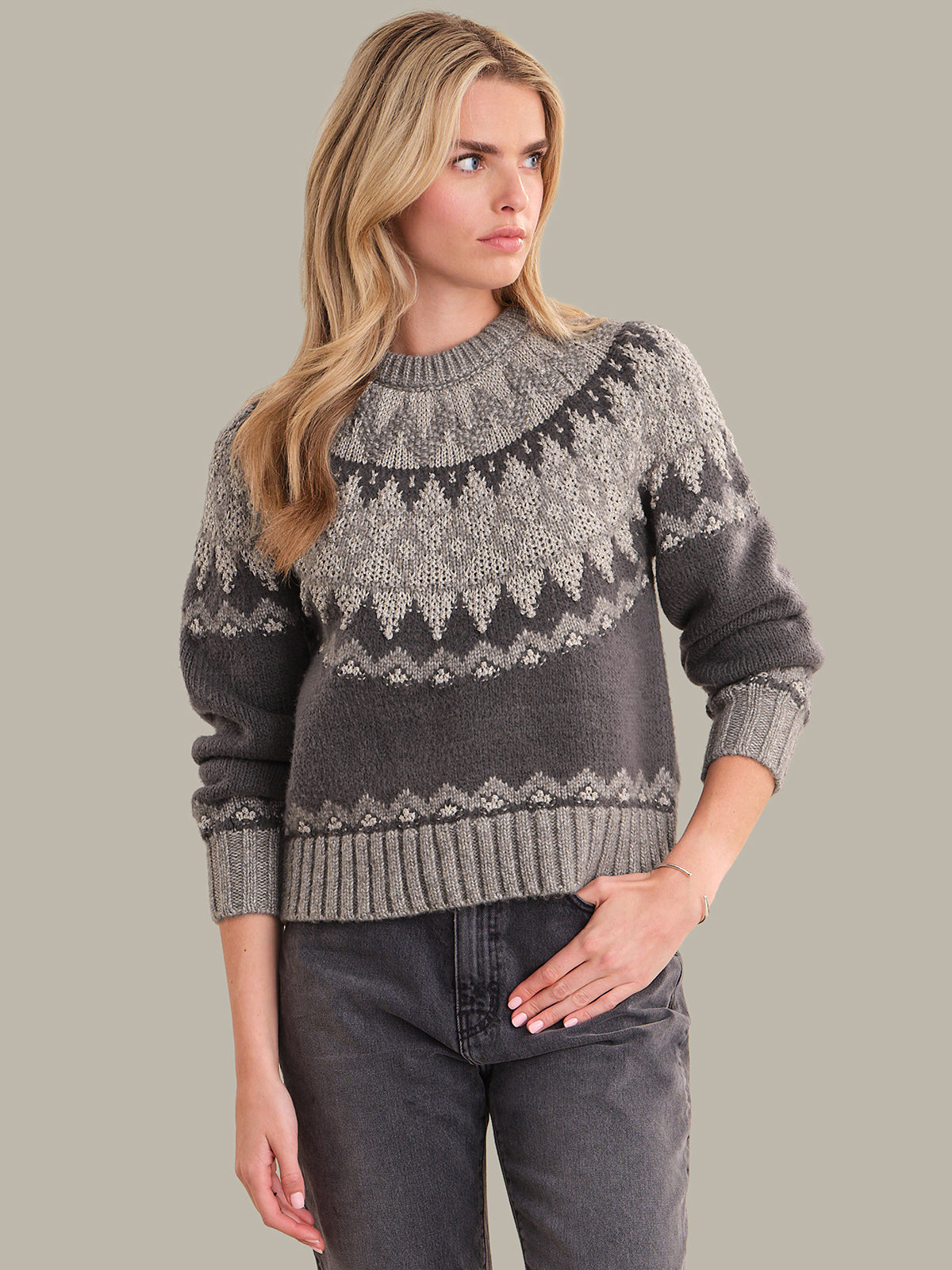 Woman wearing a gray patterned sweater against a plain background