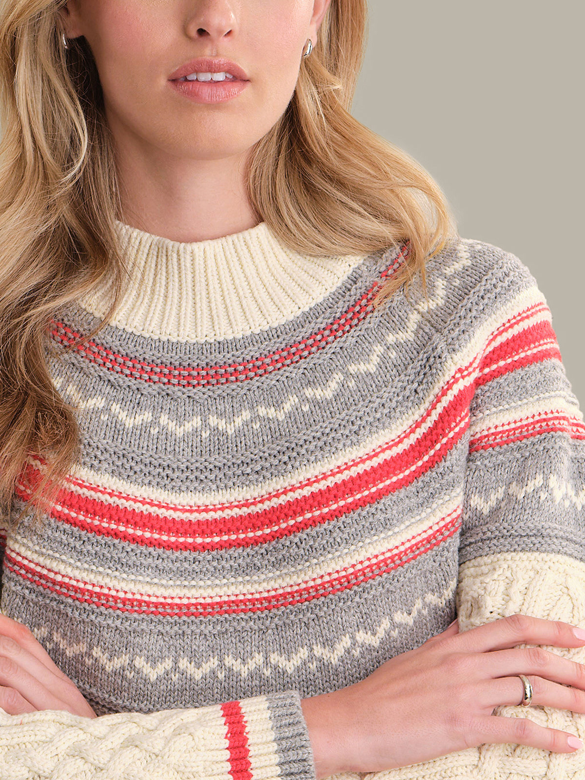 Close-up of a person wearing a patterned sweater with red and gray stripes.