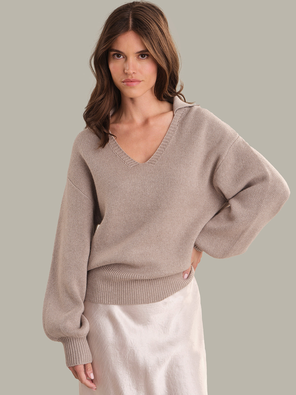 Woman wearing a beige sweater against a plain background