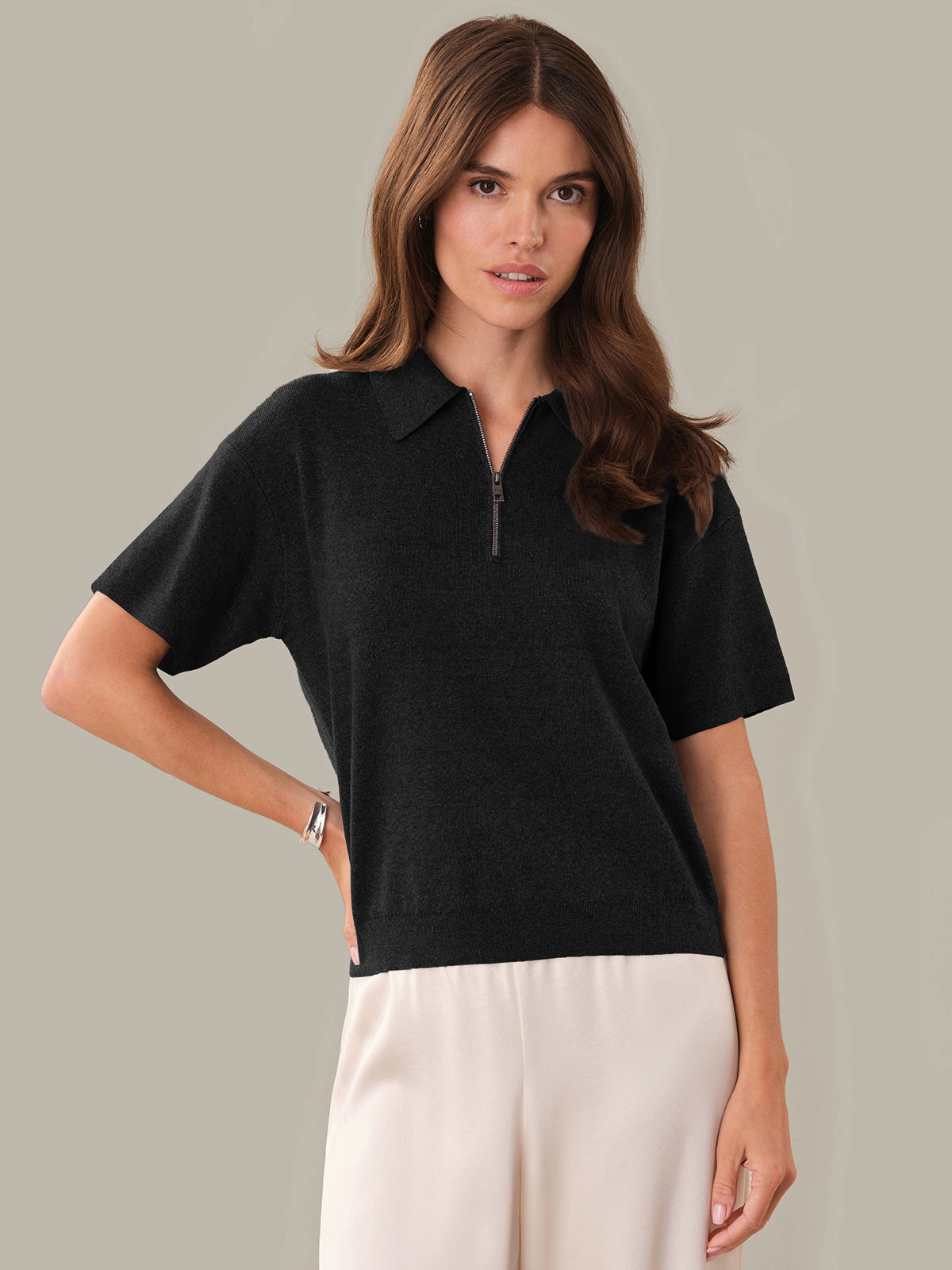 Woman wearing a black short-sleeve zip-up top against a neutral background