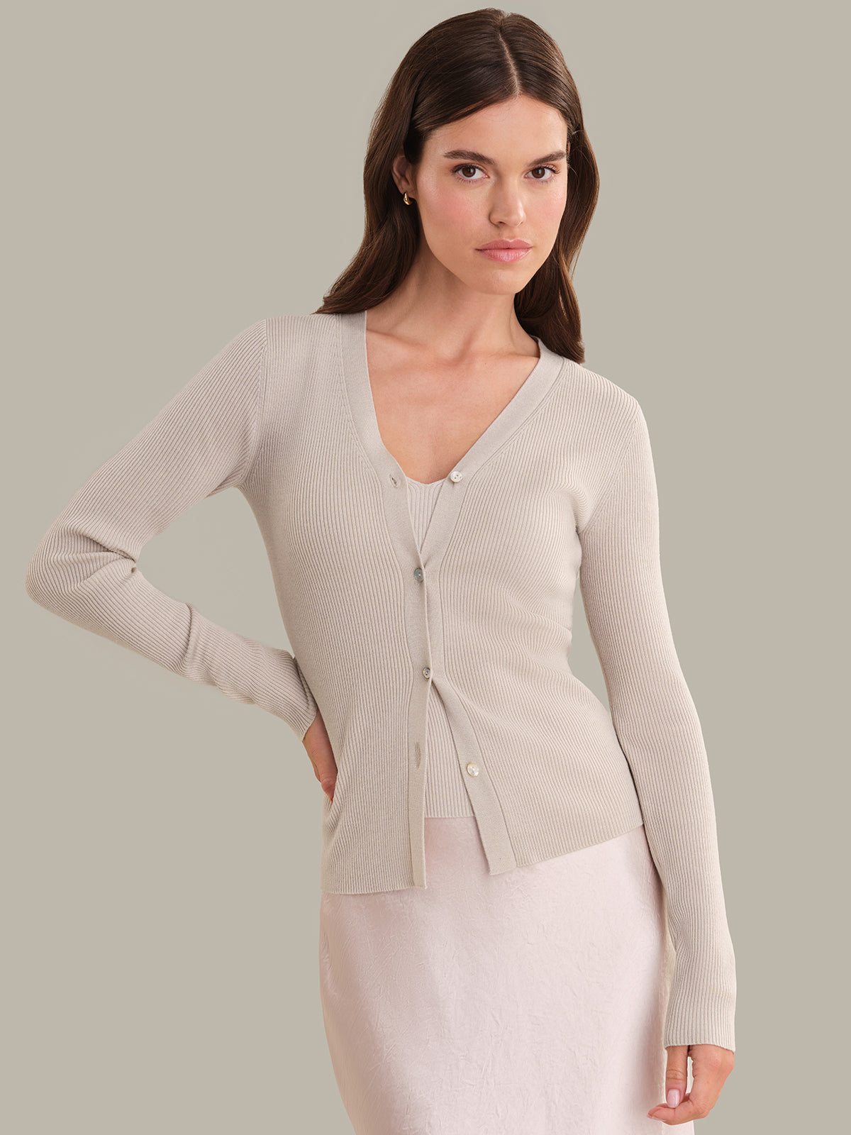 Woman wearing a beige cardigan against a plain background