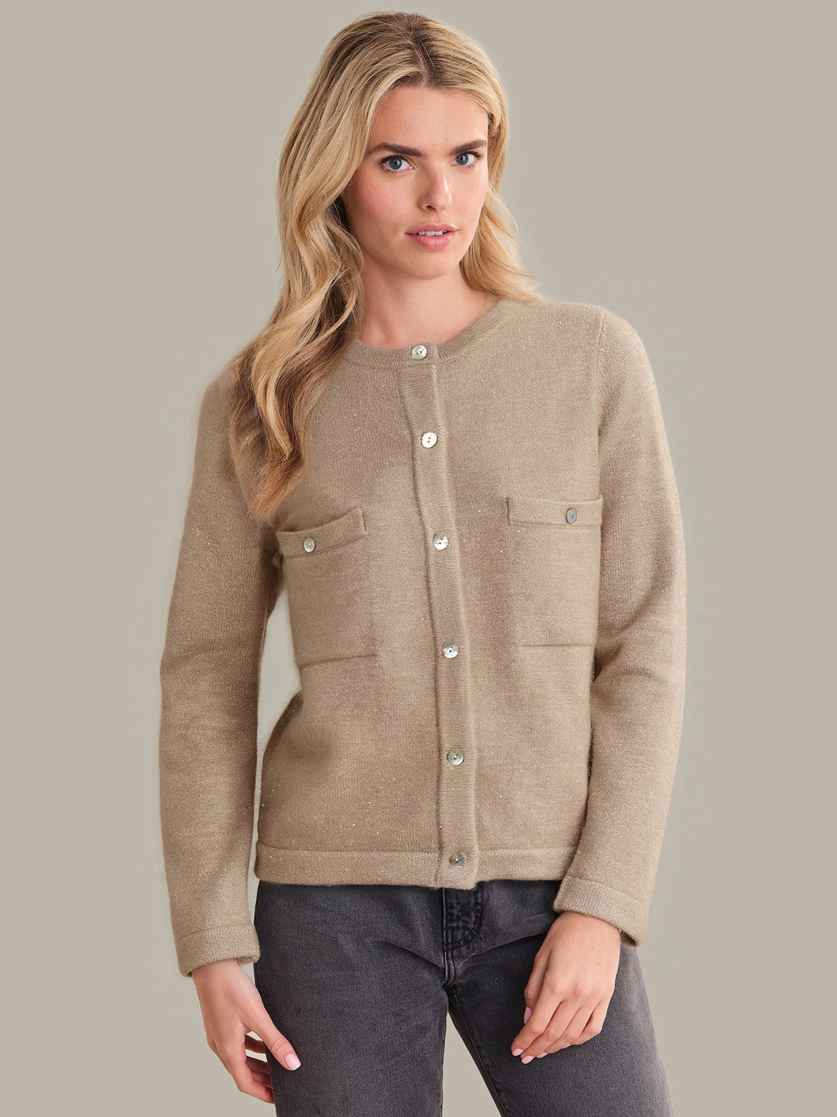 Woman wearing a beige cardigan with button details on a plain background