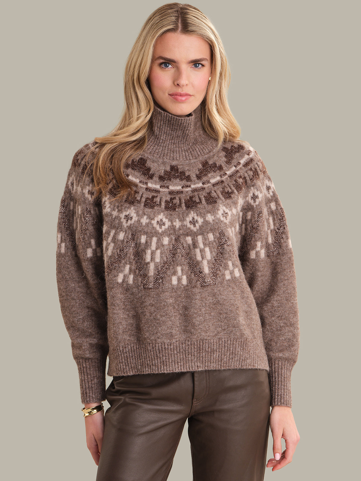 Woman wearing a patterned brown sweater against a neutral background