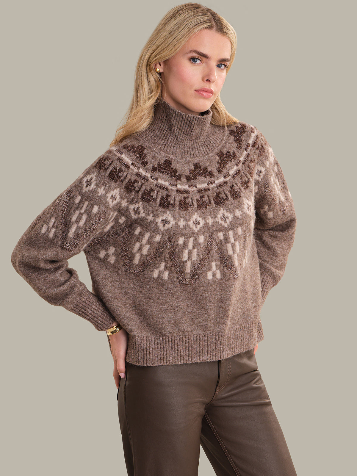 Woman wearing a brown patterned sweater against a neutral background