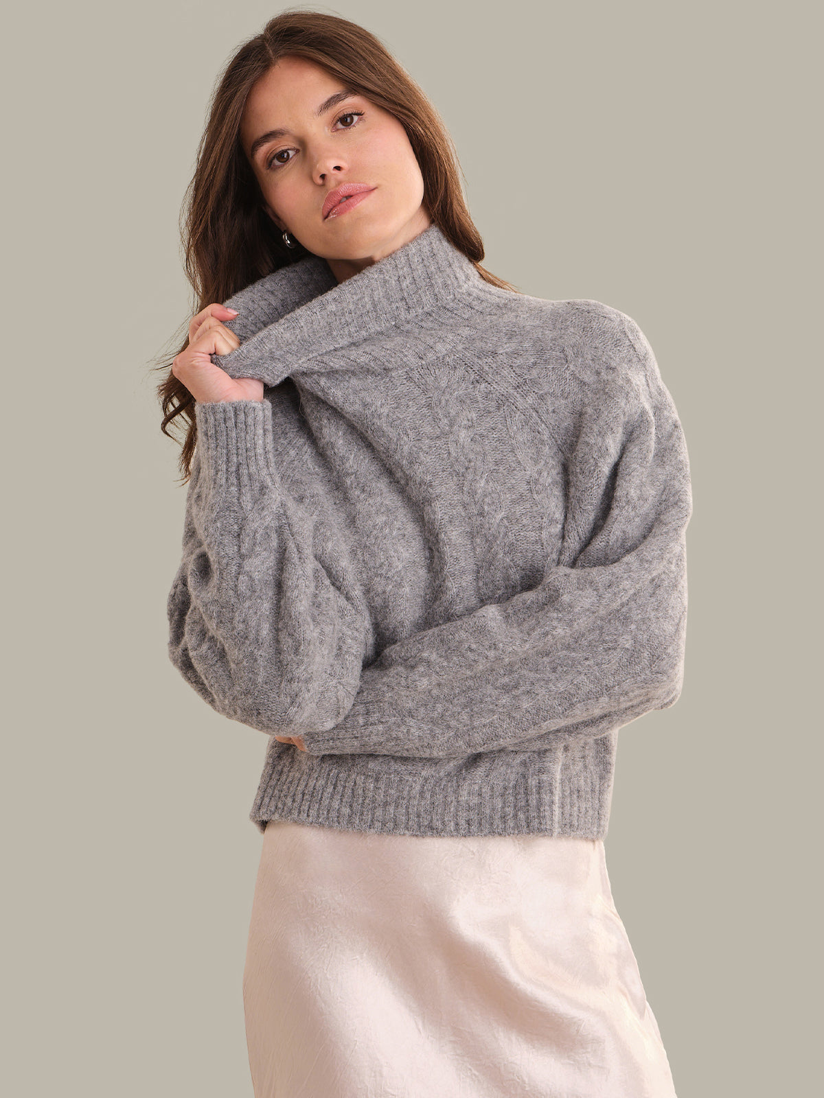 Woman wearing a gray sweater against a plain background
