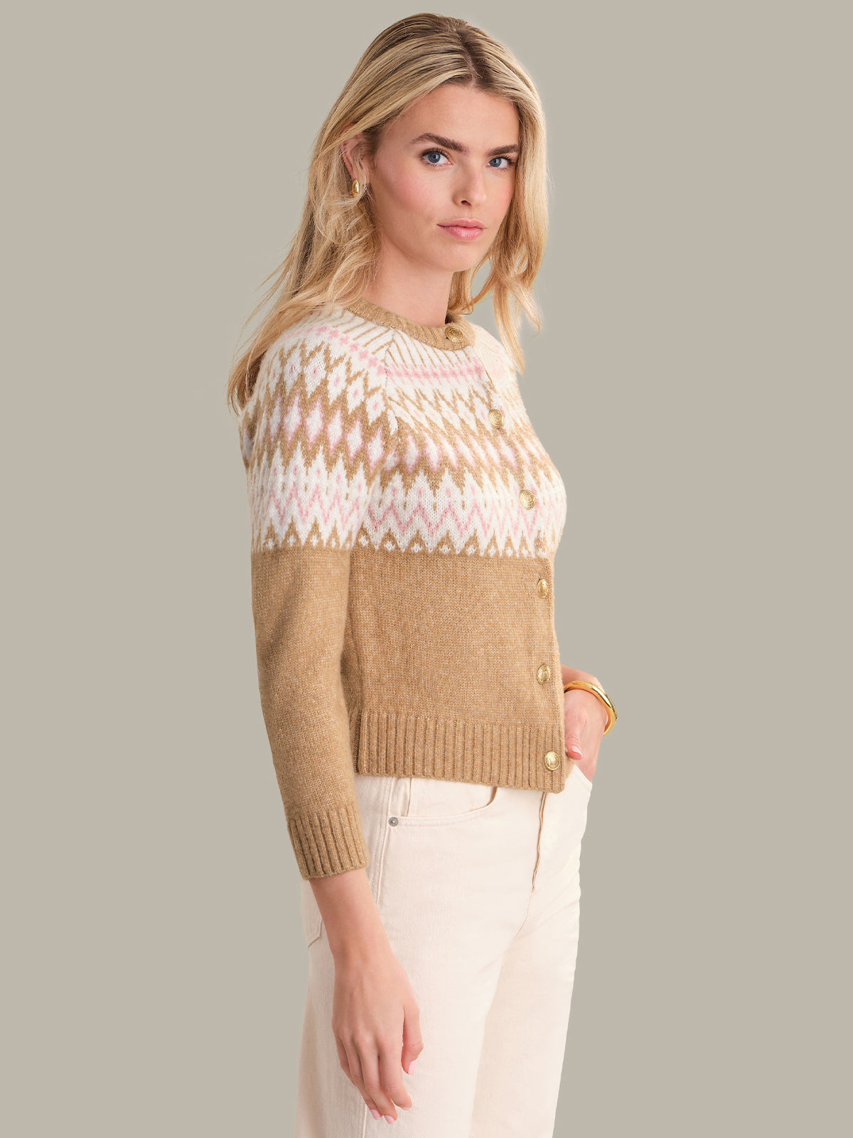 Woman wearing a beige and white patterned sweater against a plain background