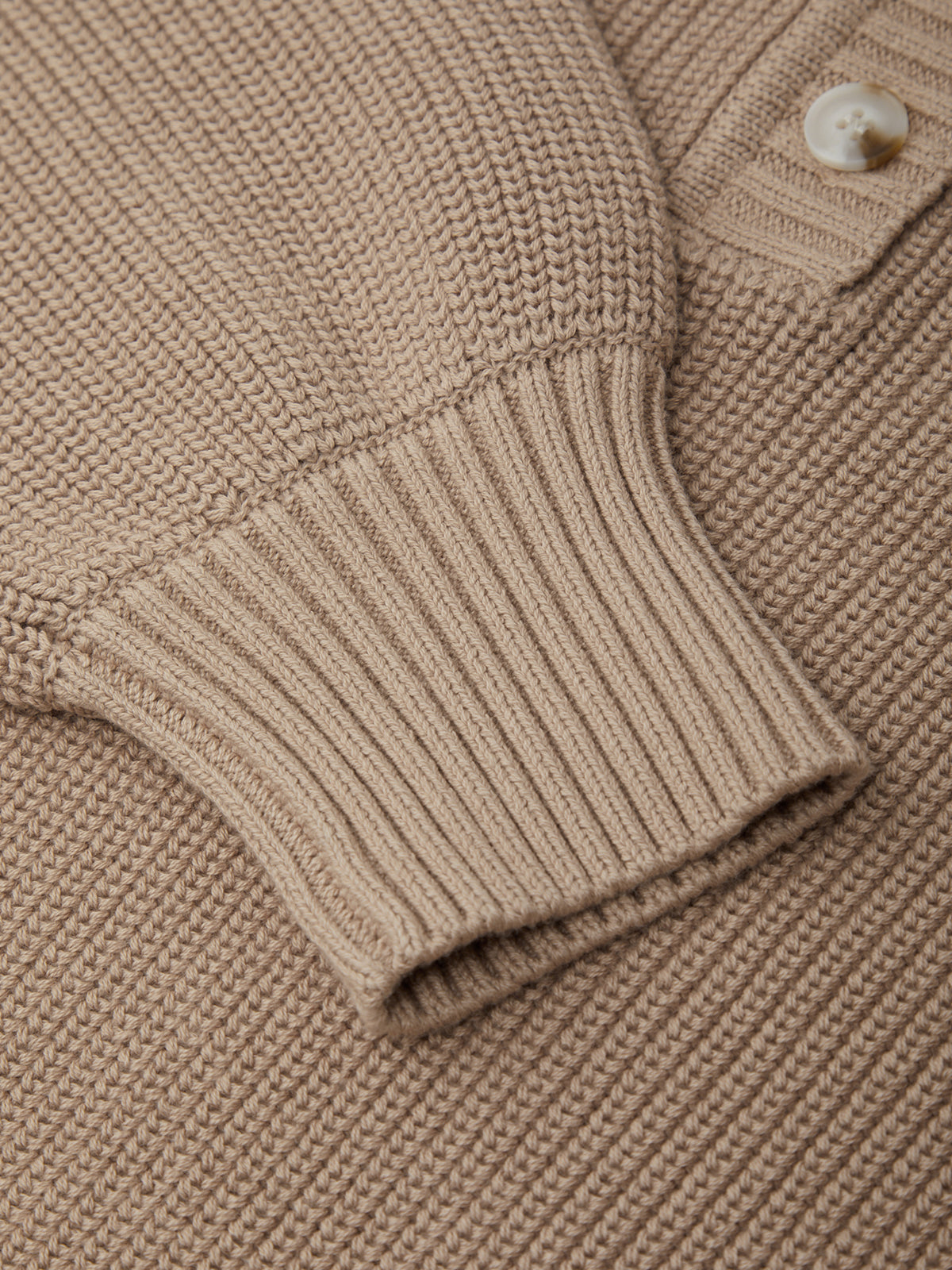 Close-up of a beige knitted sweater with a button detail
