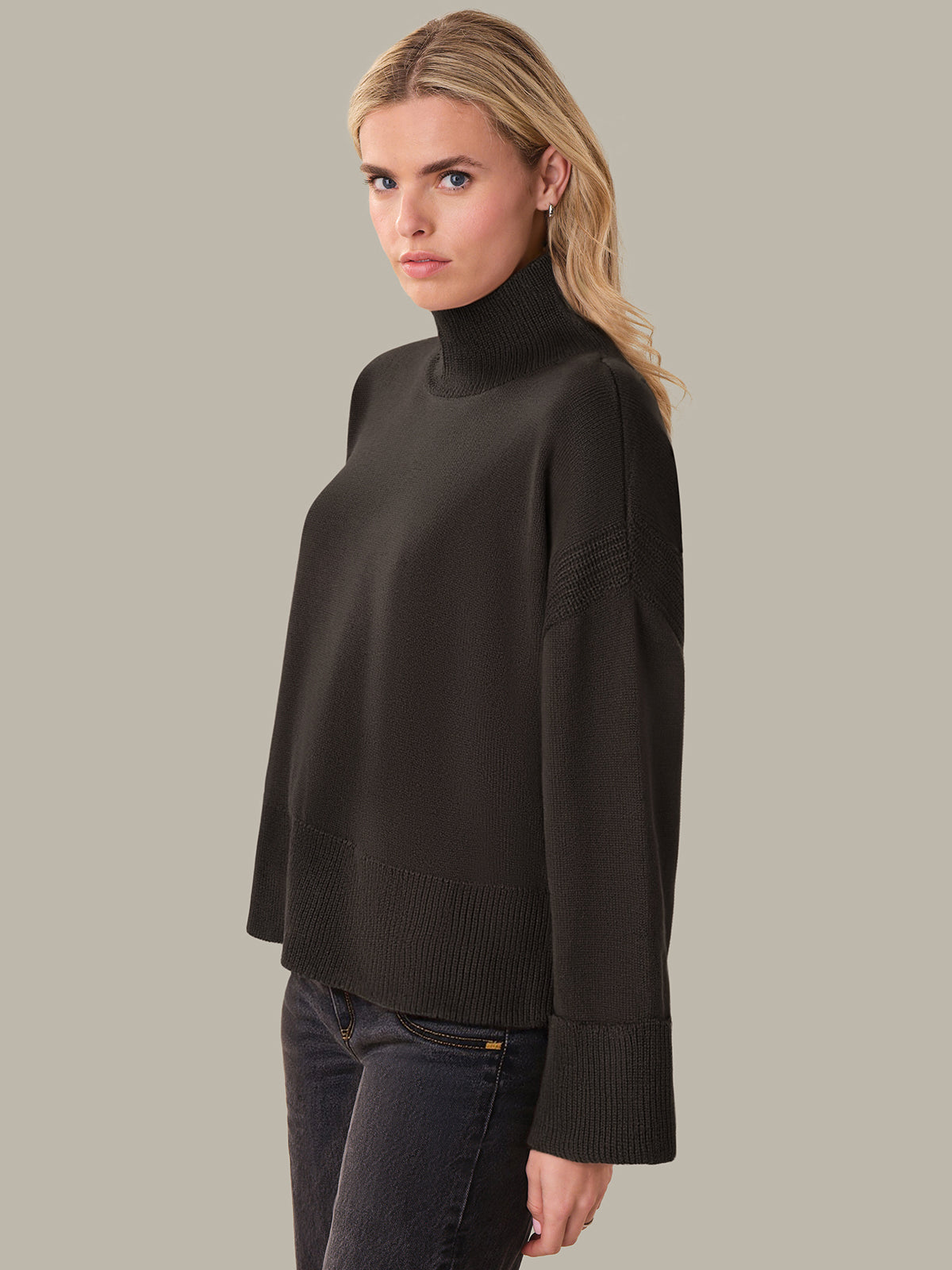 Woman wearing a brown turtleneck sweater against a plain background