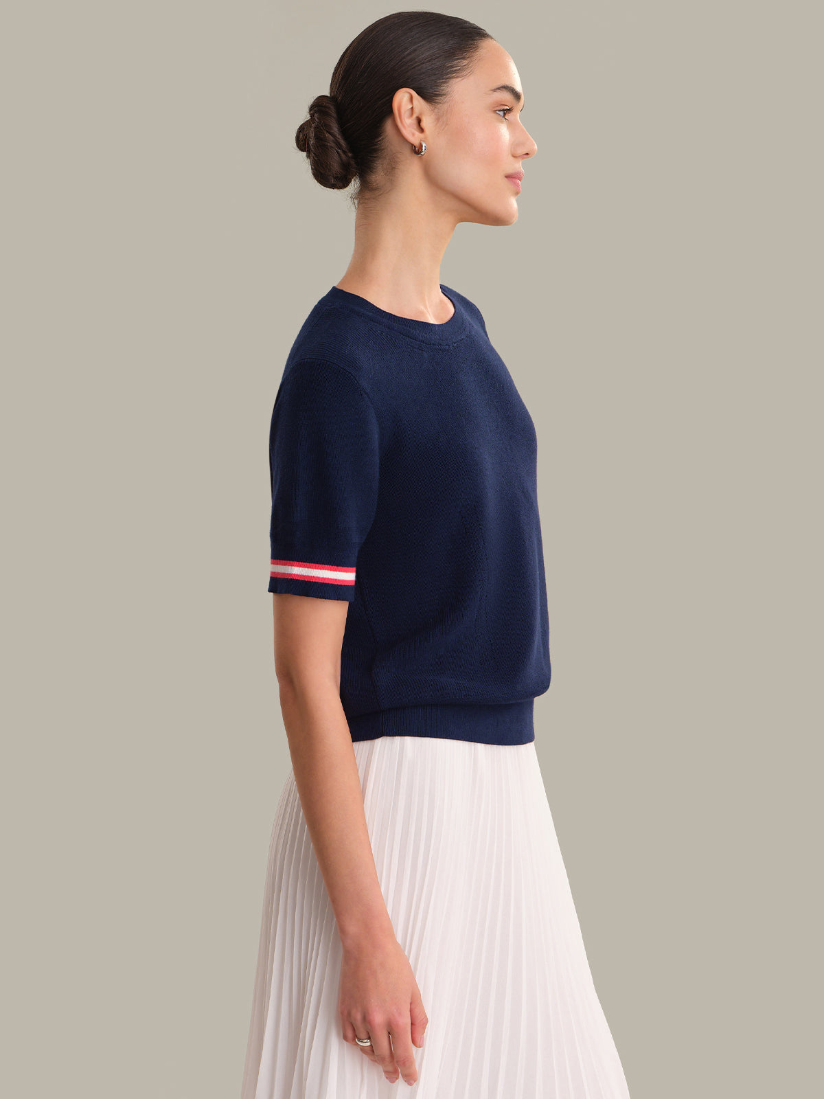 Woman wearing a navy sweater with red and white stripes on a gray background