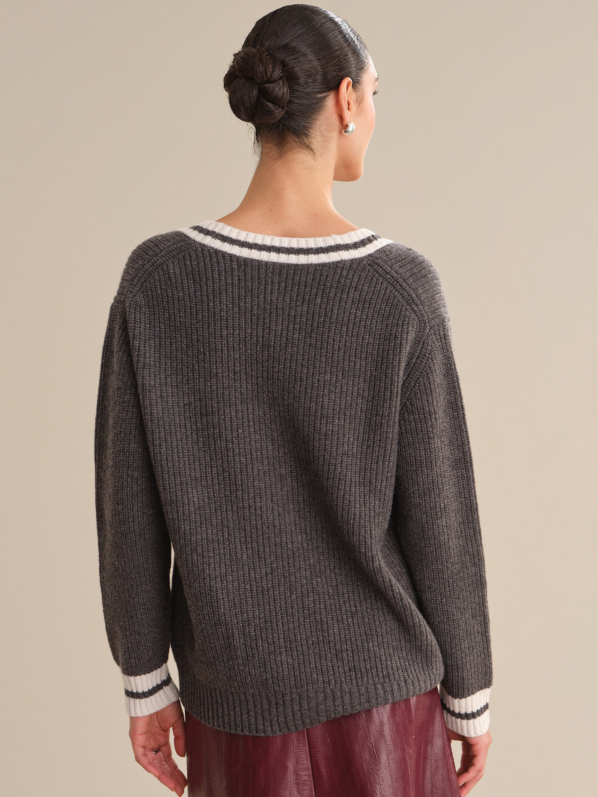 Woman wearing a gray sweater with white trim on a beige background