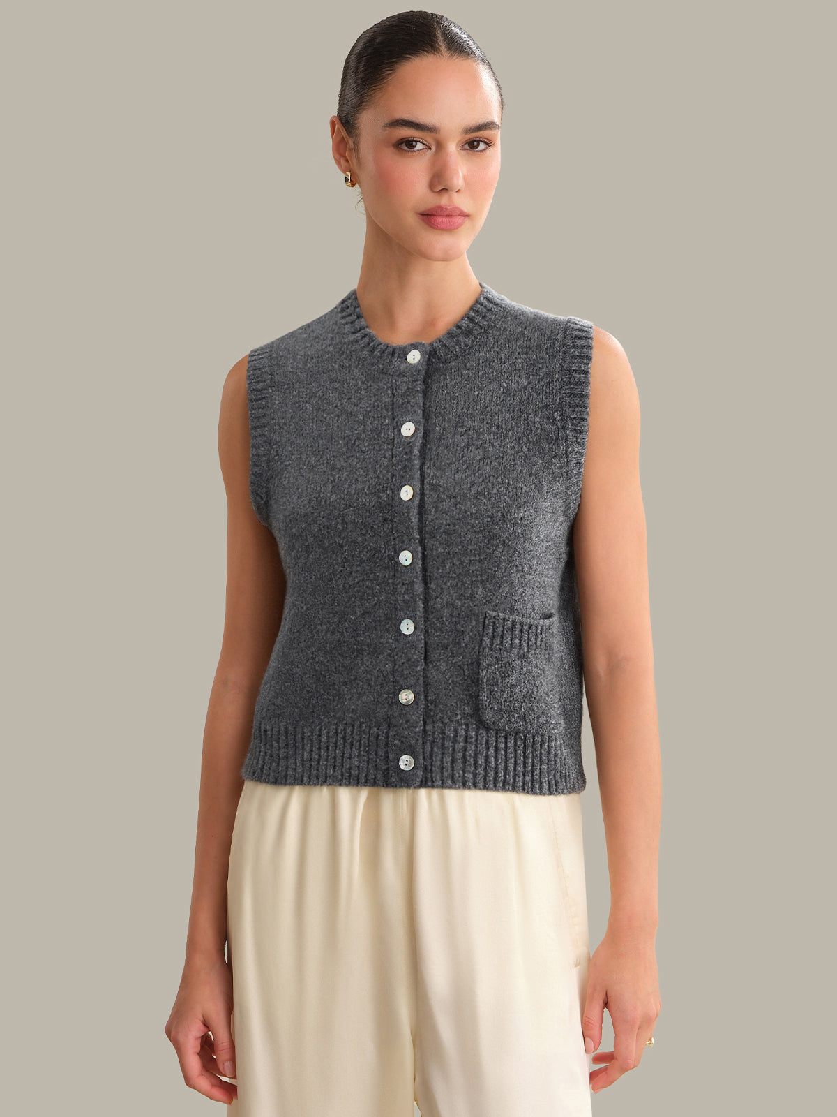 Woman wearing a gray knitted vest against a plain background