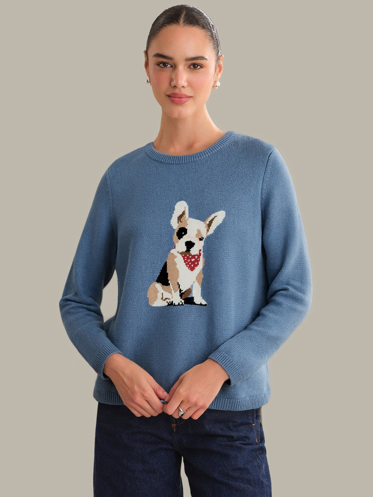 Woman wearing a blue sweater with a dog design on a plain background