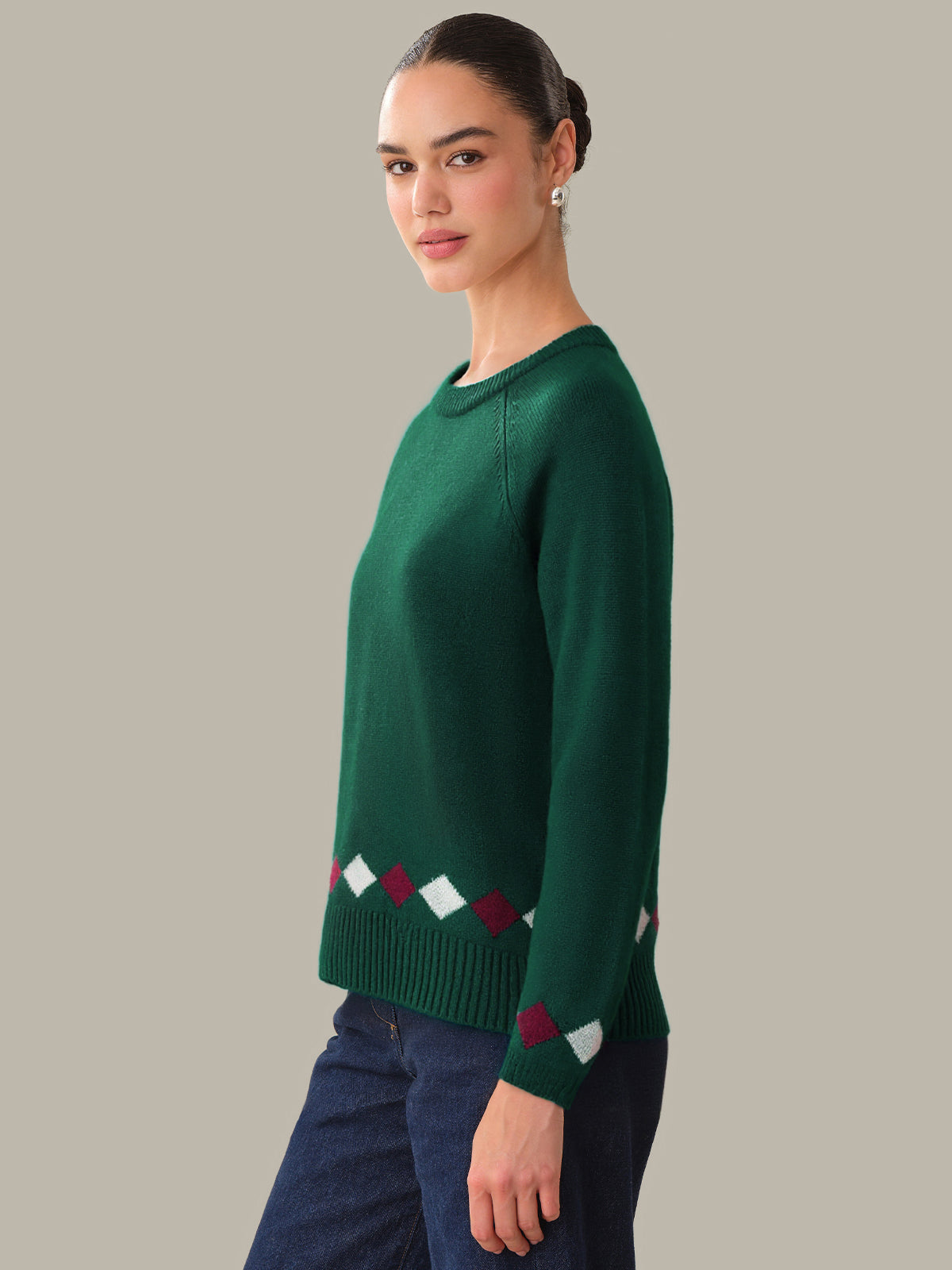 Woman wearing a green sweater with a pattern on a plain background