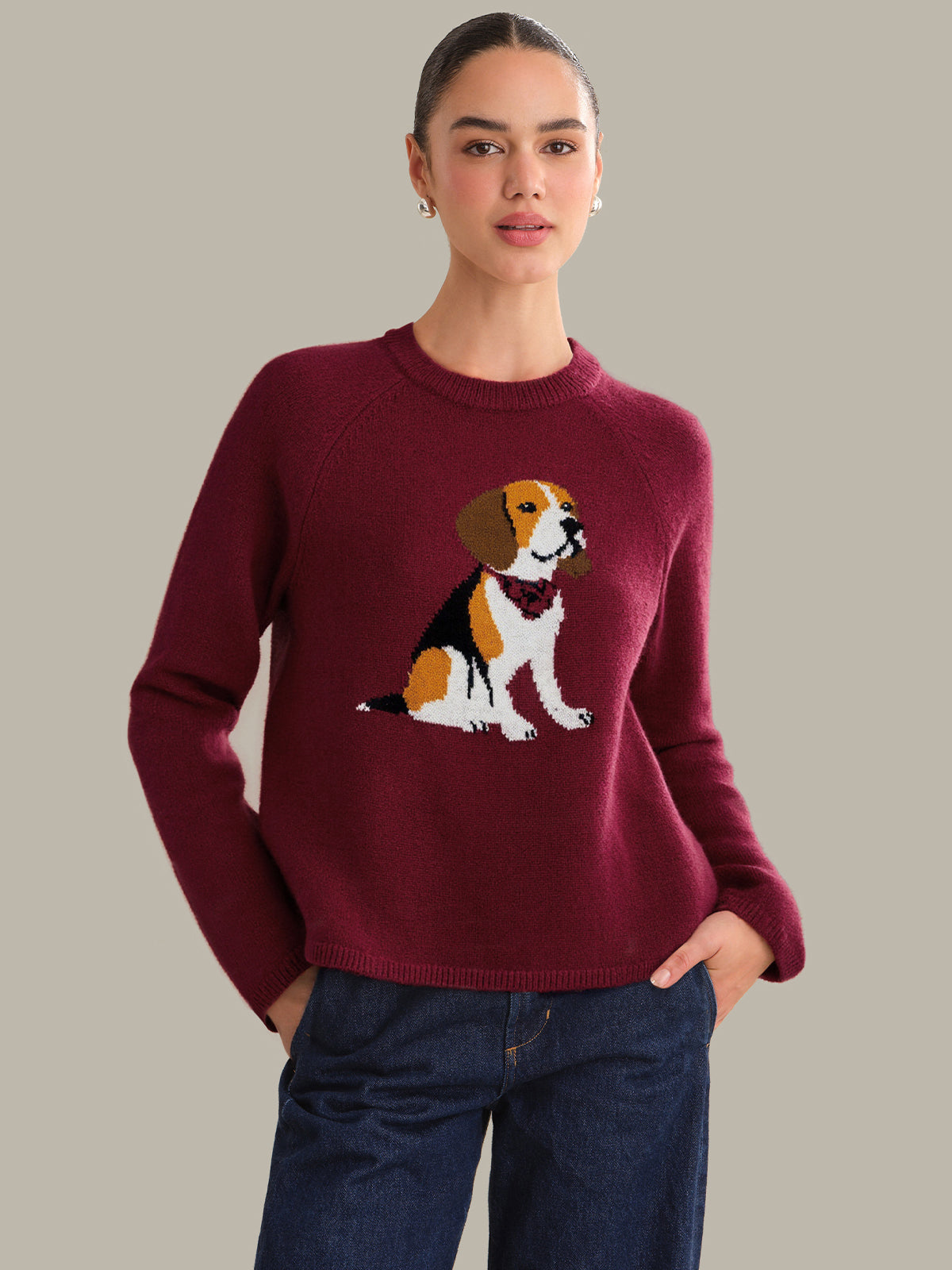 Woman wearing a burgundy sweater with a dog design on a plain background