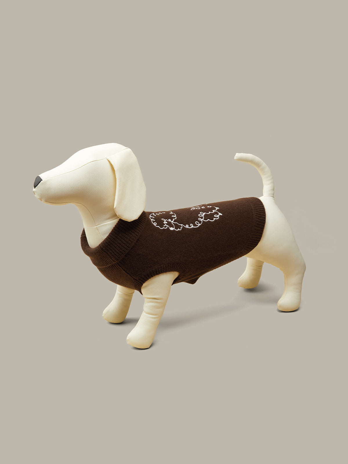 Dog wearing a brown sweater on a beige background