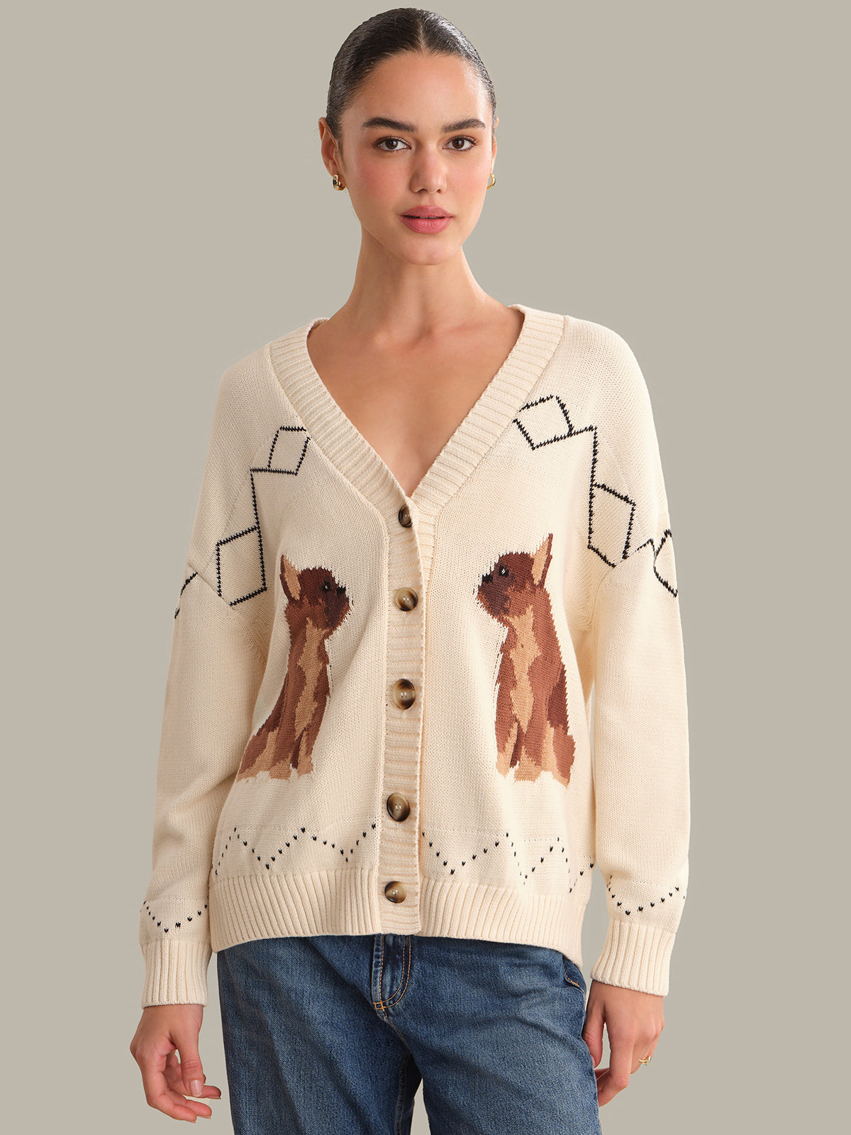 Woman wearing a cream cardigan with fox designs on a gray background