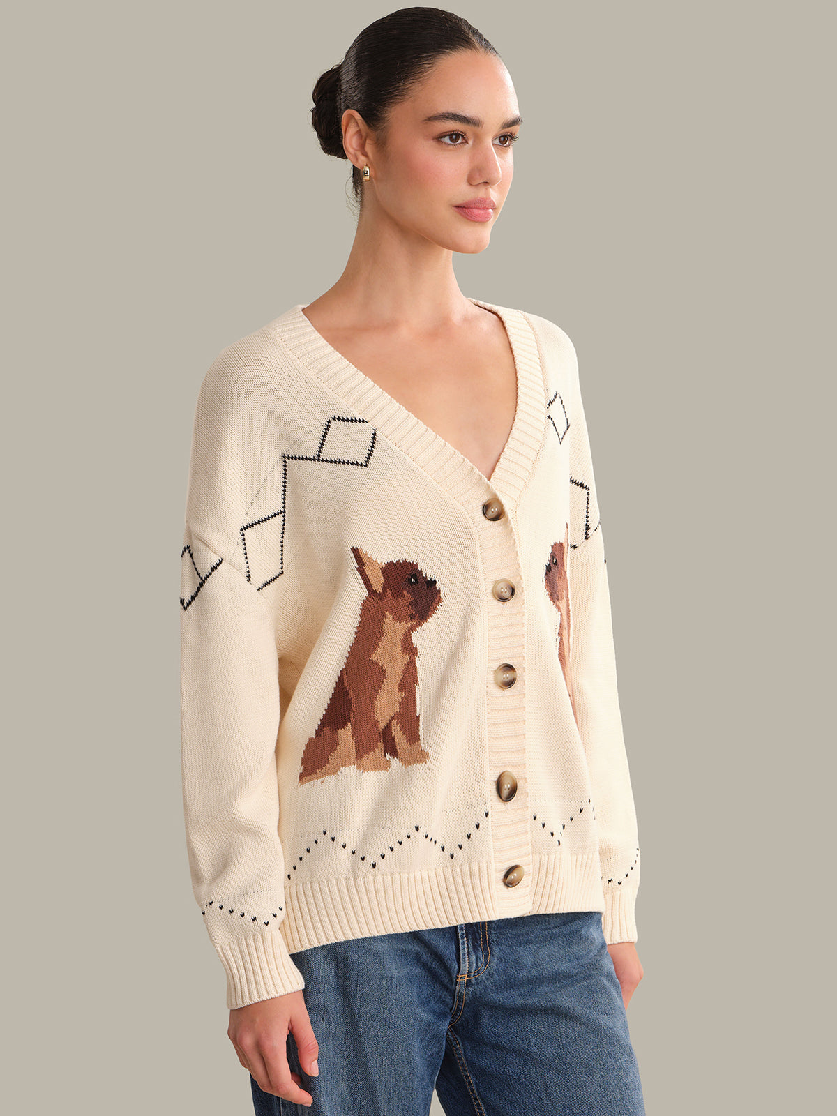 Woman wearing a cream cardigan with dog illustrations on a gray background