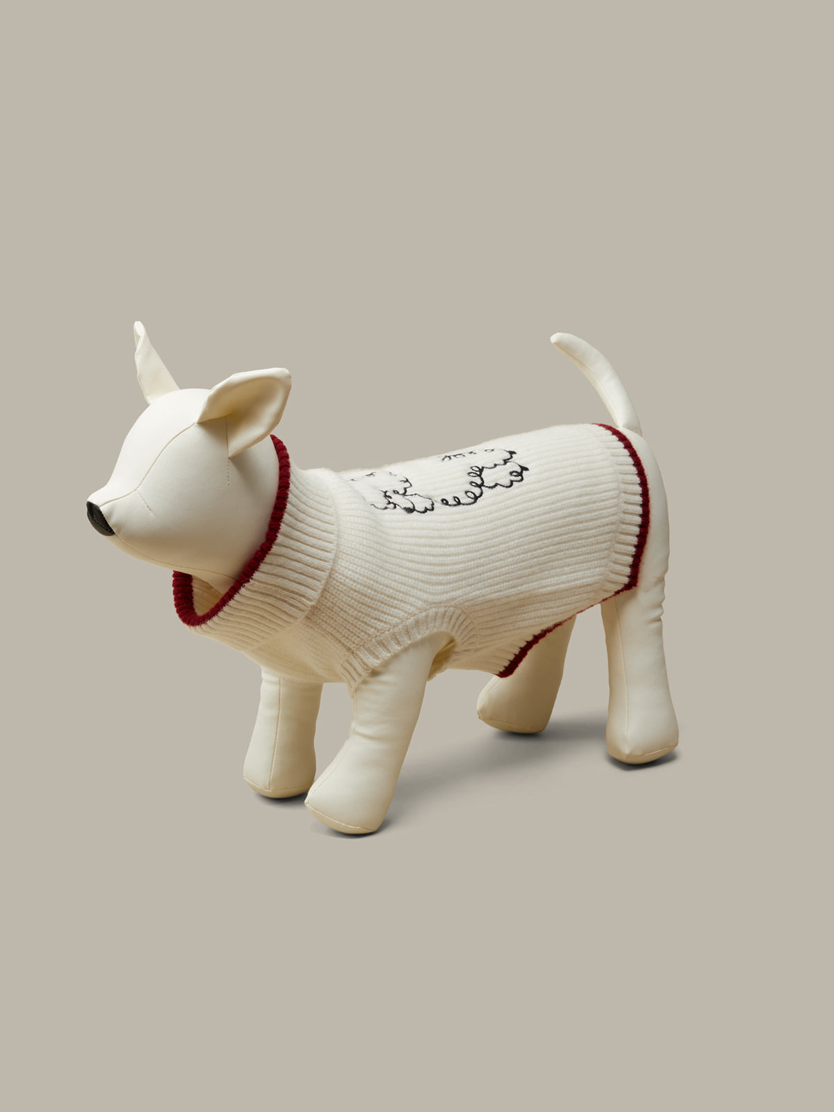 Dog figurine wearing a sweater on a beige background