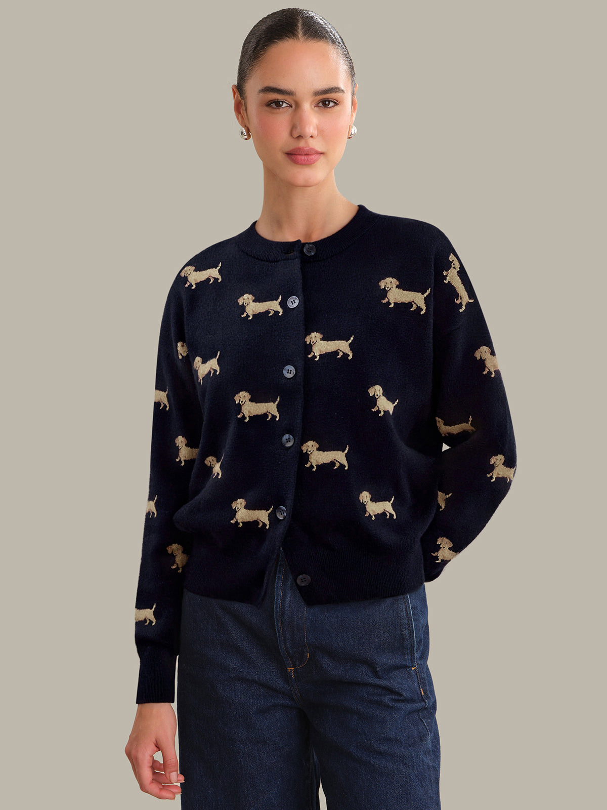 Woman wearing a navy cardigan with dog pattern on a plain background