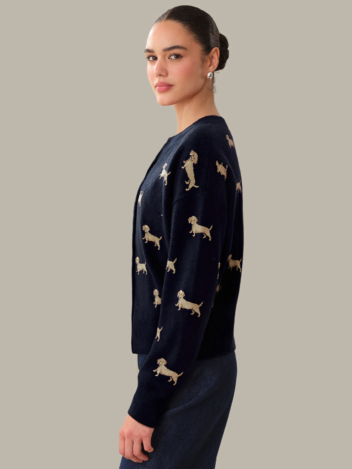 Woman wearing a navy sweater with dog patterns on a plain background