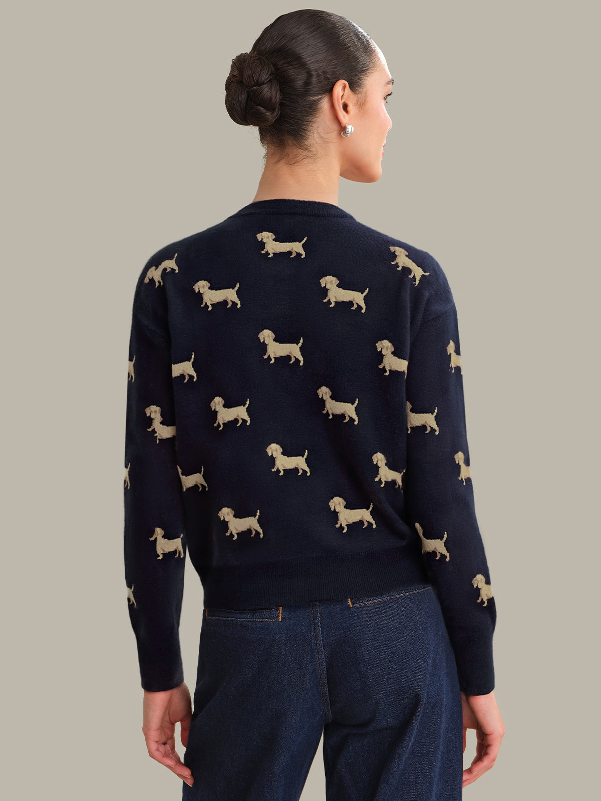 Person wearing a navy sweater with dog pattern on a plain background