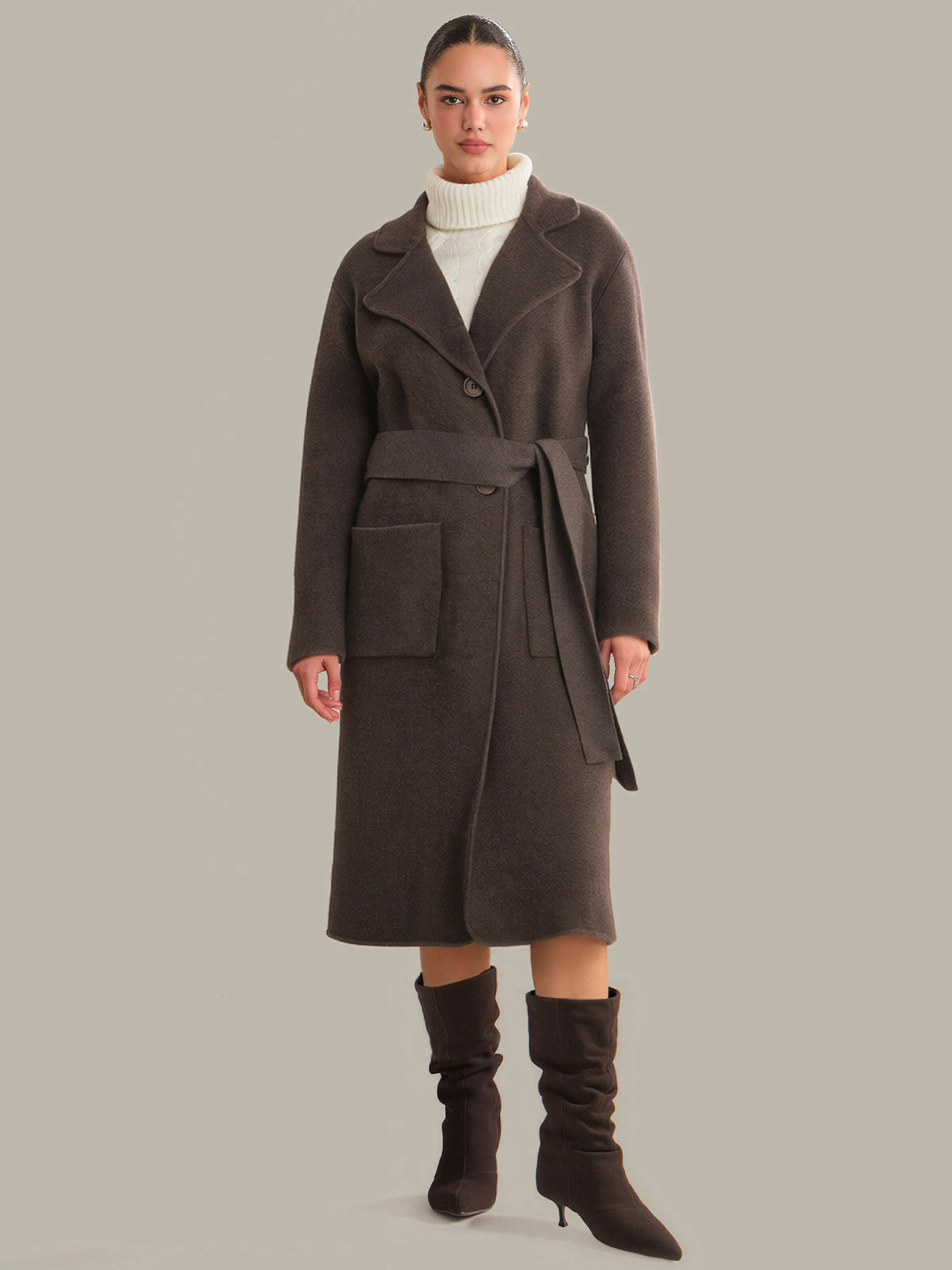 Woman wearing a long brown coat on a gray background