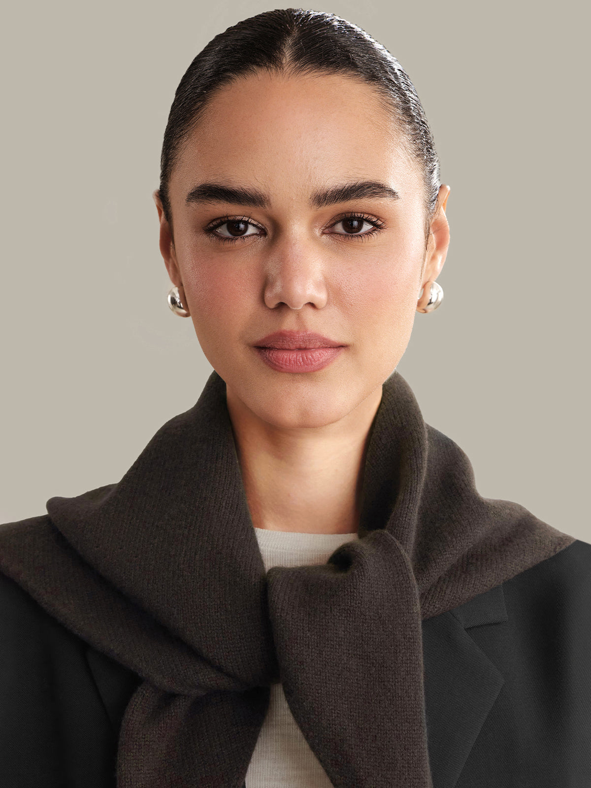 Woman wearing a dark brown scarf against a neutral background