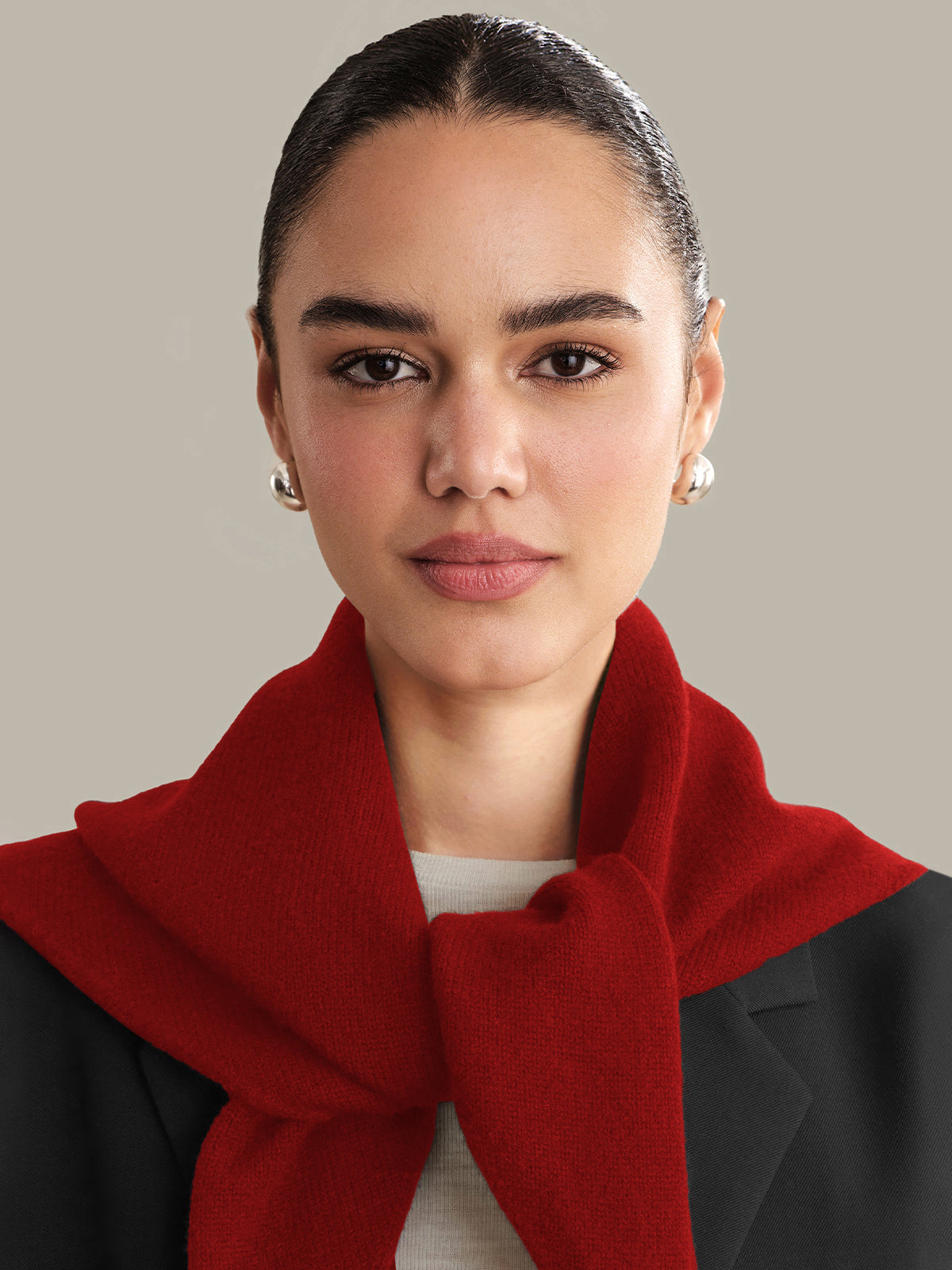 Woman wearing a red scarf against a neutral background