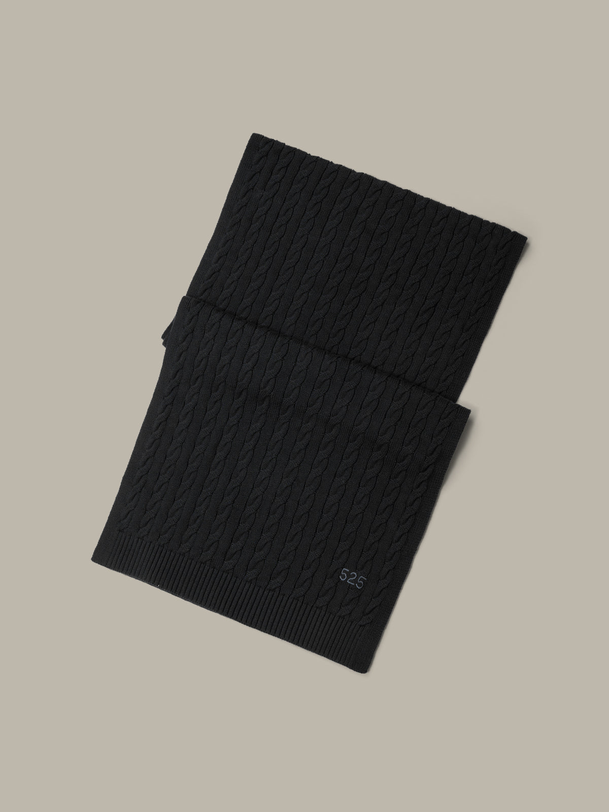 Black ribbed knit scarf on a beige background